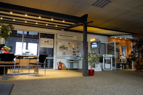 Moderner Ausstellungsraum zu Hausautomation mit Infotafeln, Möbeln und Pflanzen.