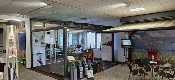 Moderne Ausstellung mit Markisen, Glasüberdachung, Gartenmöbeln und Smart-Home-Steuerungen.