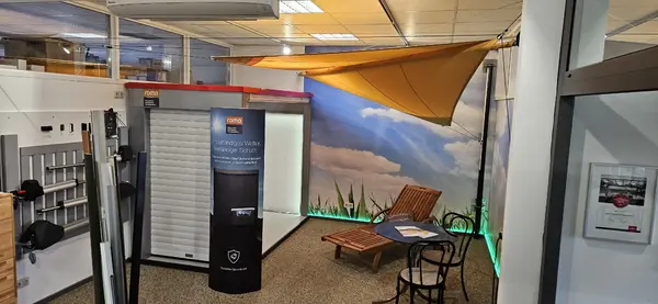 Ausstellung mit Sonnensegel, Rollladen, Gartenmöbeln und Infotafel in modernem Showroom.