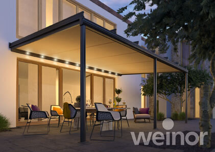 Moderne Terrassenüberdachung mit LED-Beleuchtung und Gartenmöbeln bei Einbruch der Dämmerung.